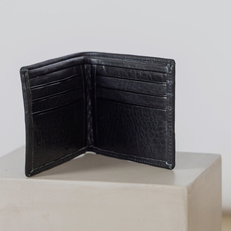Black leather wallet open on a white surface with a light gray background