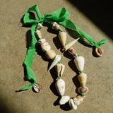 Seashell necklace with a green ribbon on a textured surface